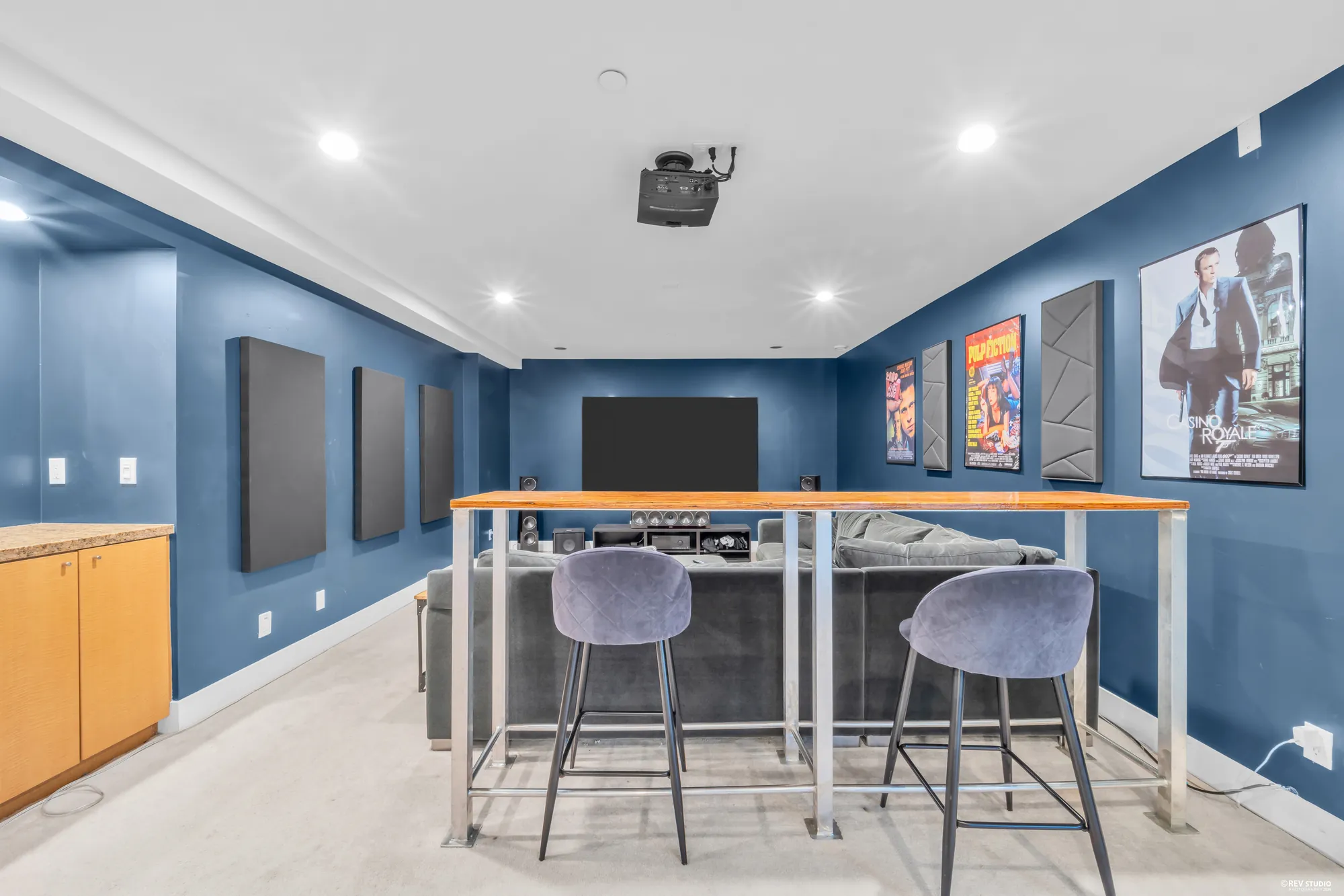 The bar counter with stools between the two rooms, the screen and posters beyond