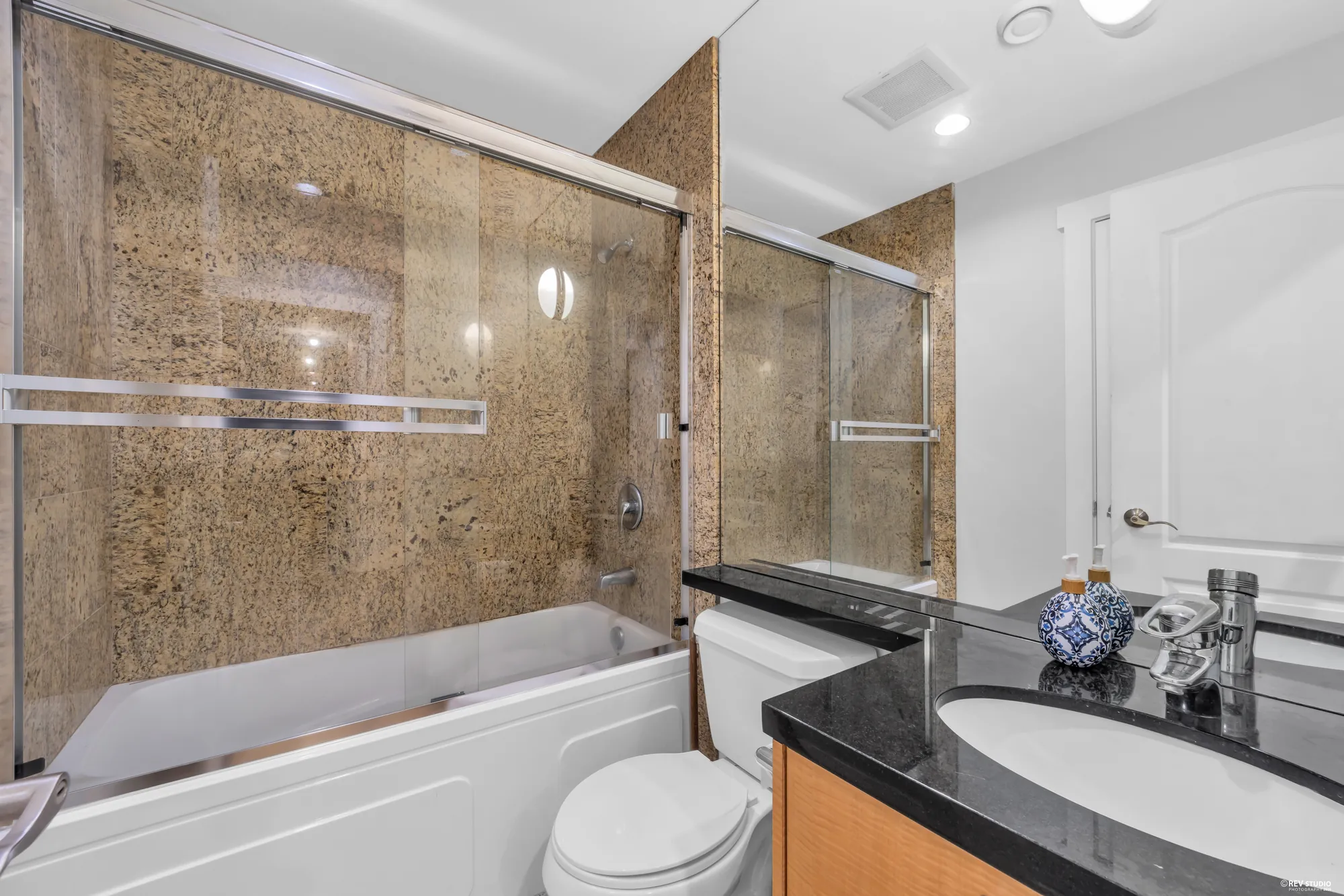 The other lower bathroom: a tub and shower in granite, a dark stone counter