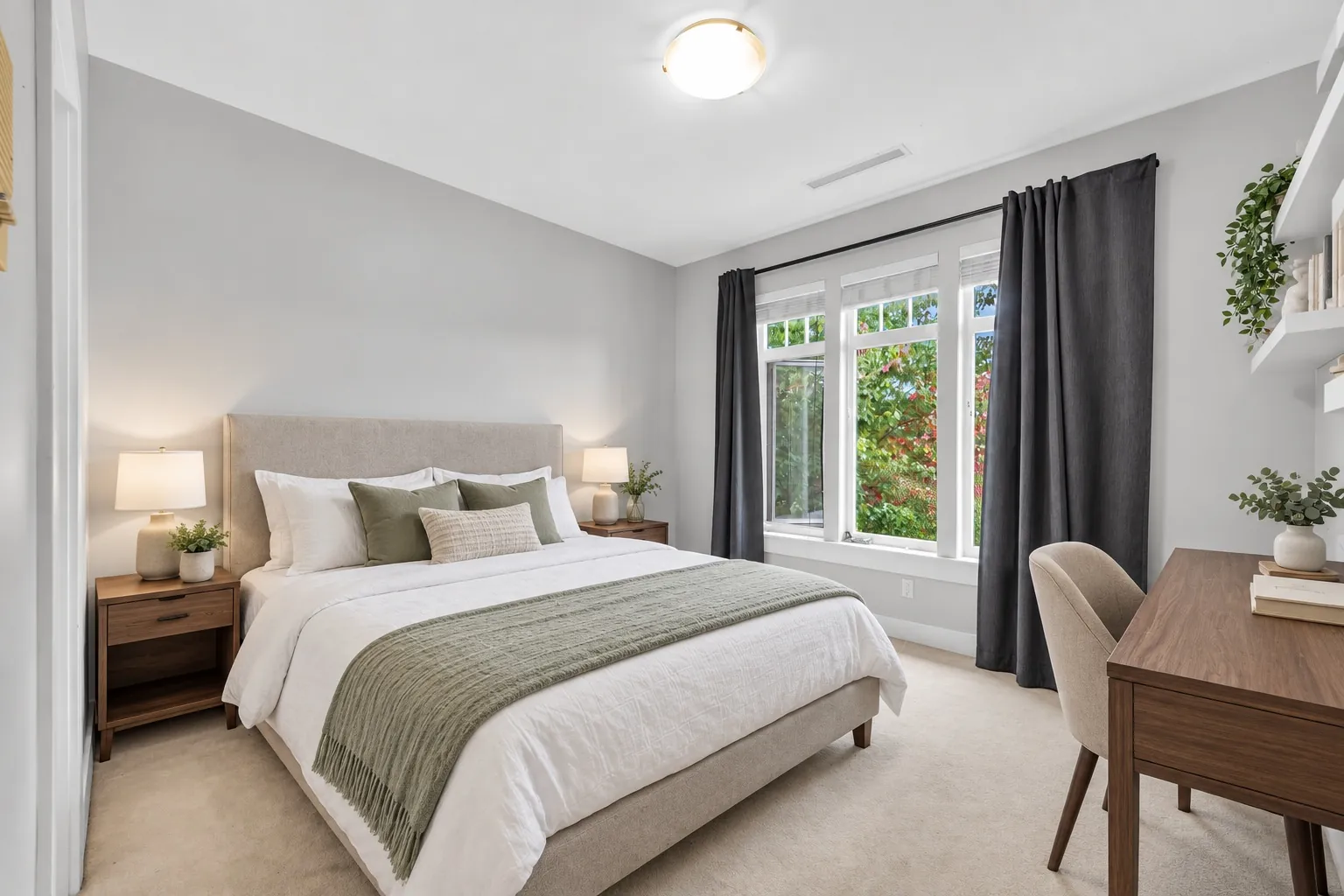 A bedroom virtually staged with a bed, nightstands, lamps and a desk, the window with grey curtains