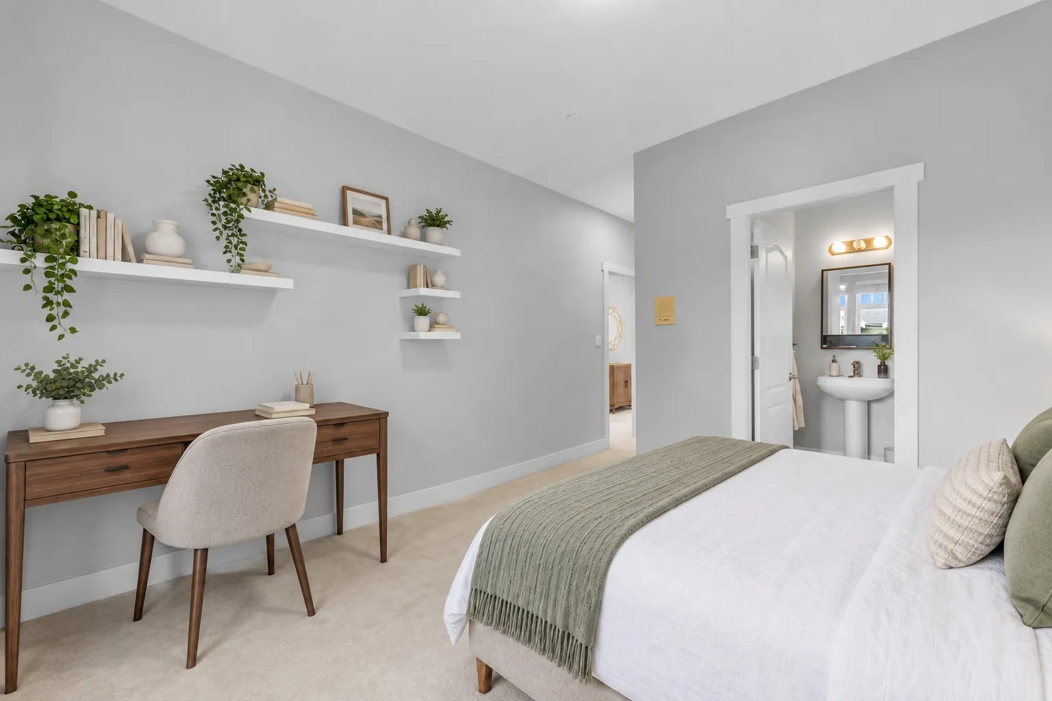 A bedroom under a sloped ceiling, virtually staged with a bed, a desk and chair and dressed shelves, its bathroom through the door