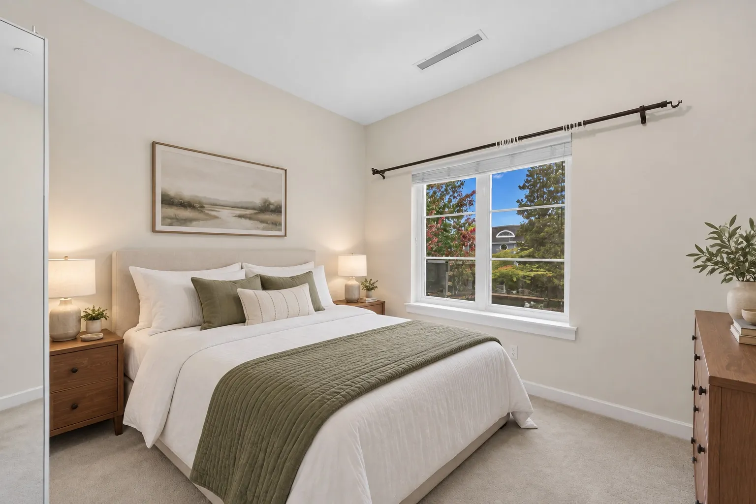 A bedroom under a sloped ceiling, virtually staged with a bed, nightstands, a picture and a dresser, one window