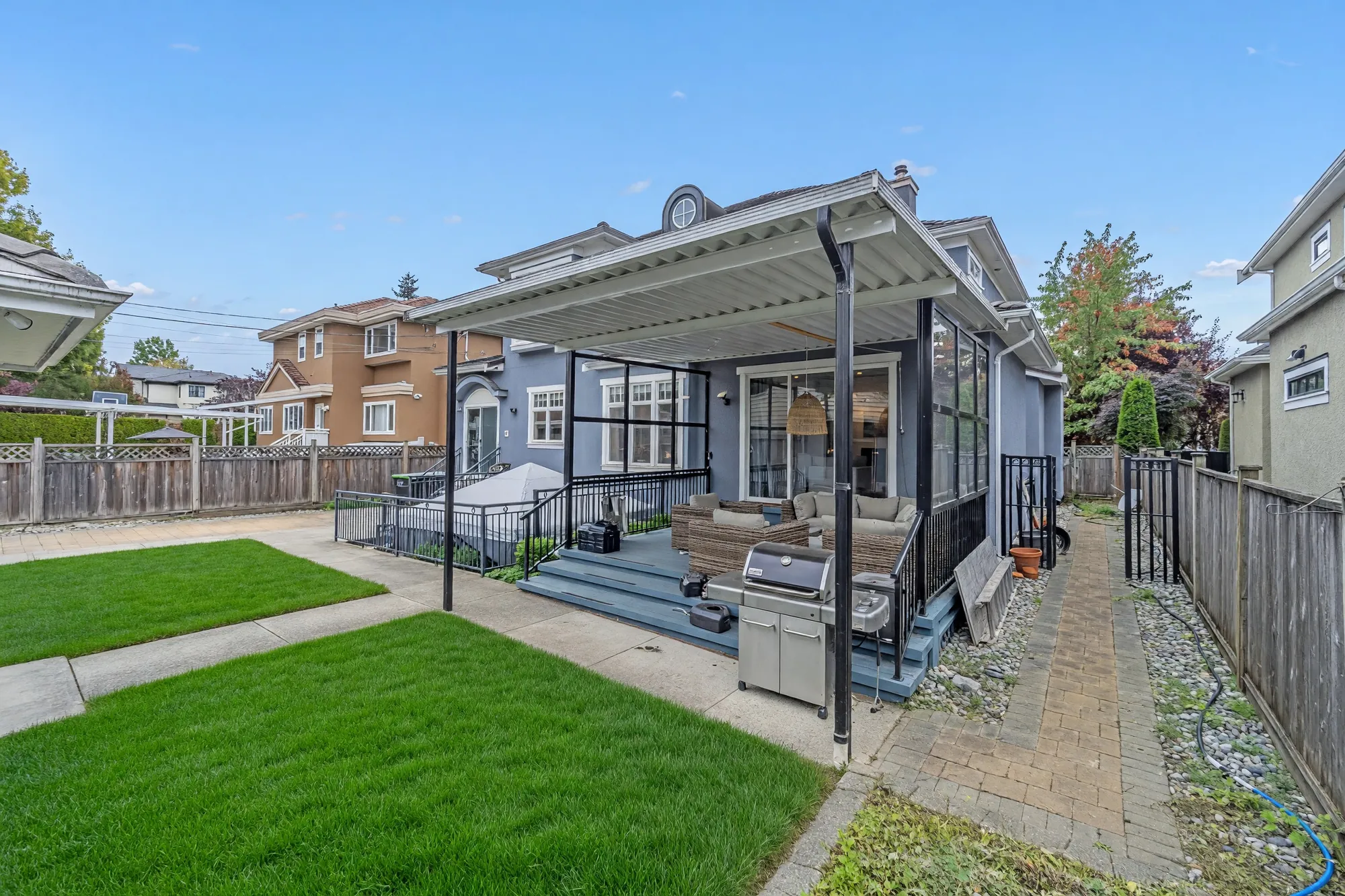 The covered deck with its barbecue, the lawn and the path to the garage