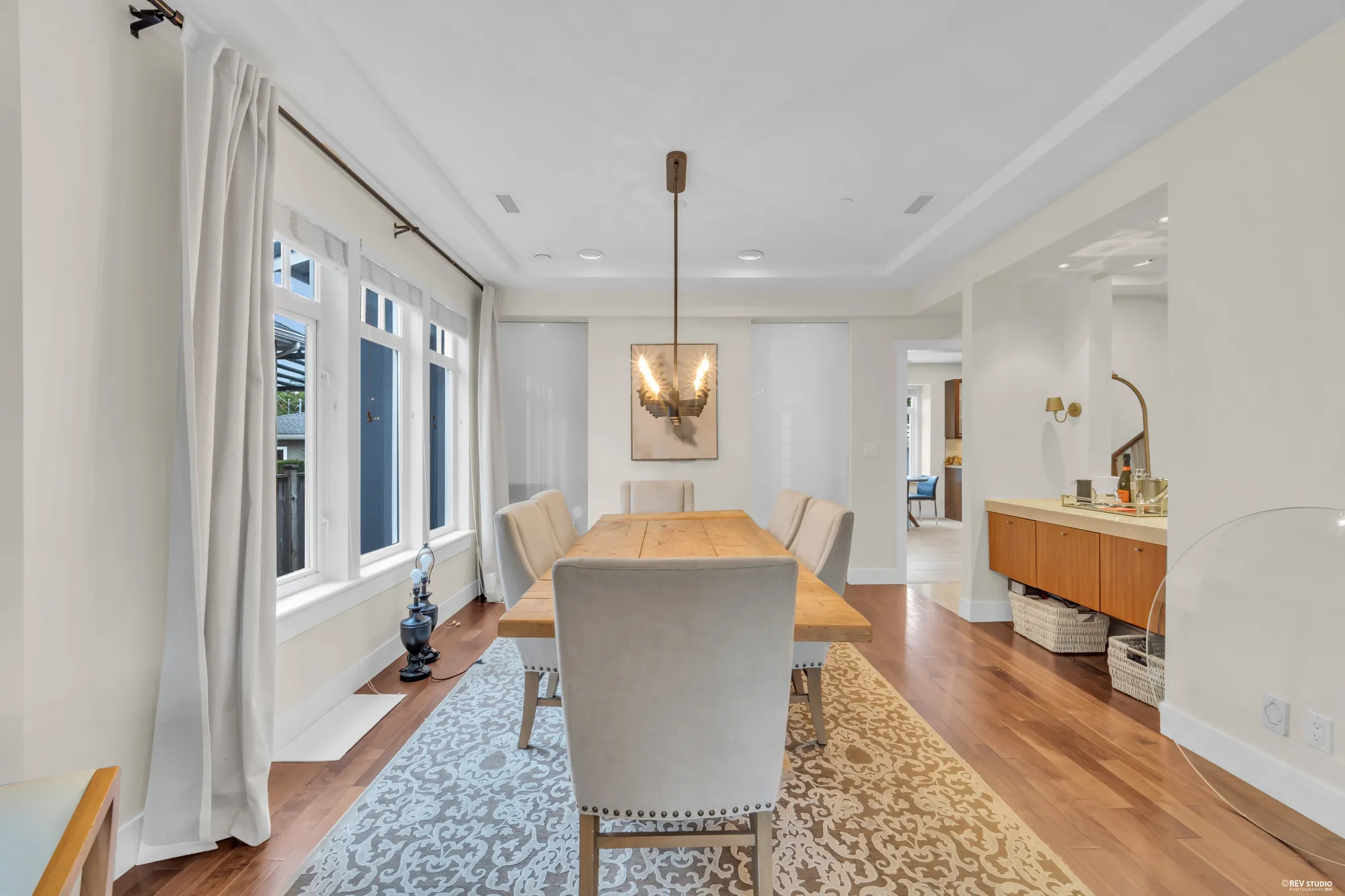 The dining table by the window, a pendant above it, the hall beyond