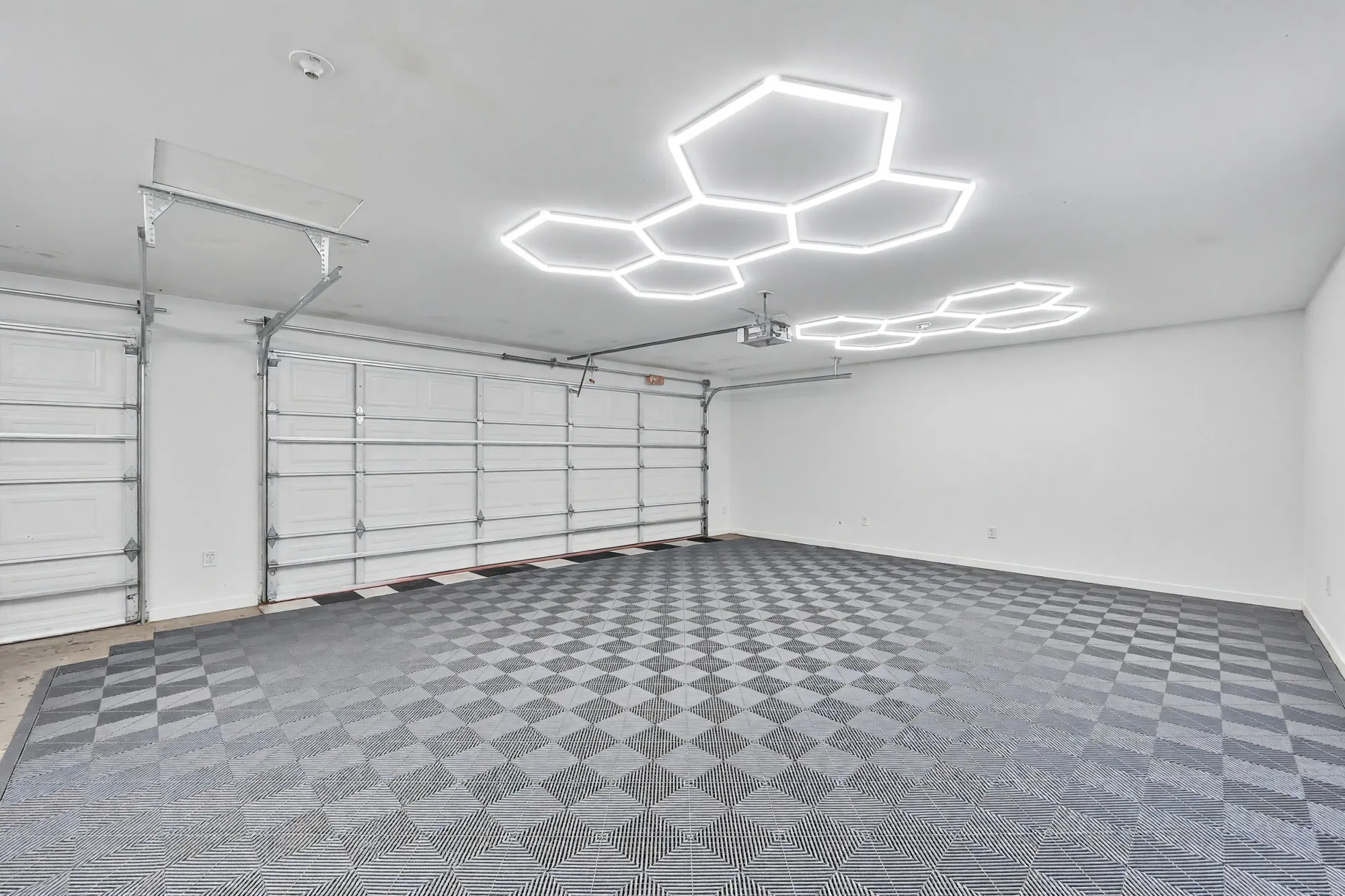 Inside the garage: a tiled floor in grey and black, hexagonal lights on the ceiling, the doors along the far wall