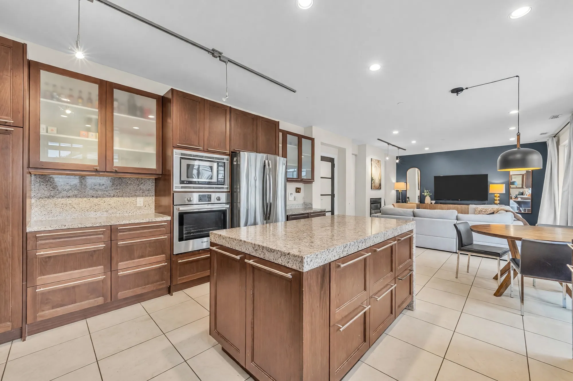 The kitchen toward the family room, the wall ovens and fridge at left