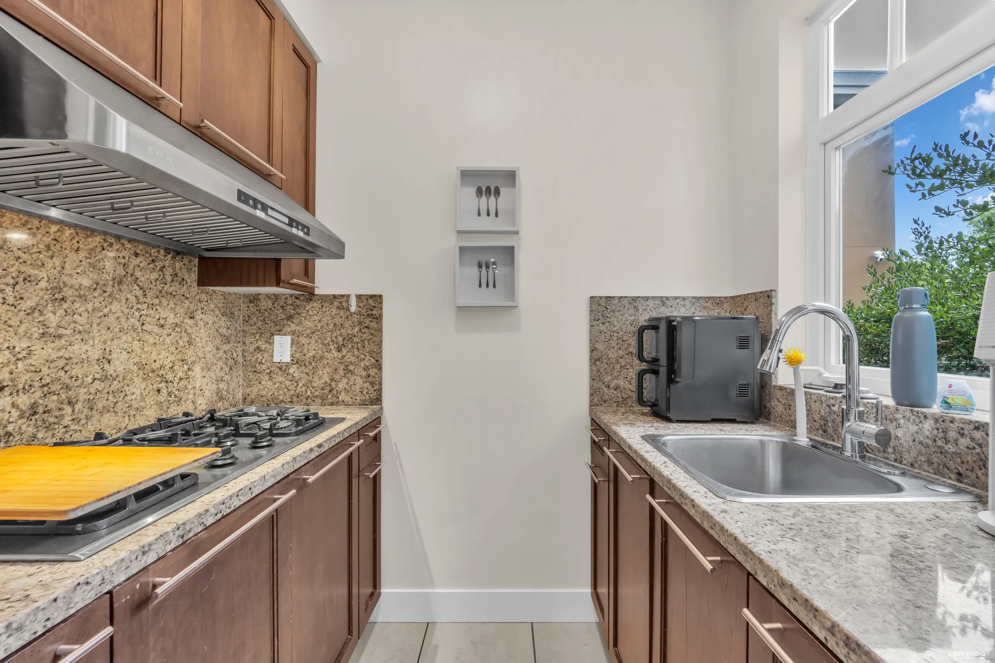 The gas cooktop under its hood, the sink under the window