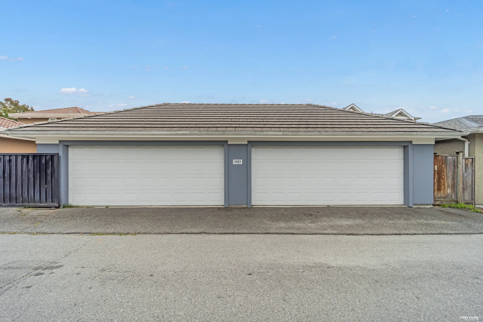 The garage from the lane: a hipped roof over two white garage doors