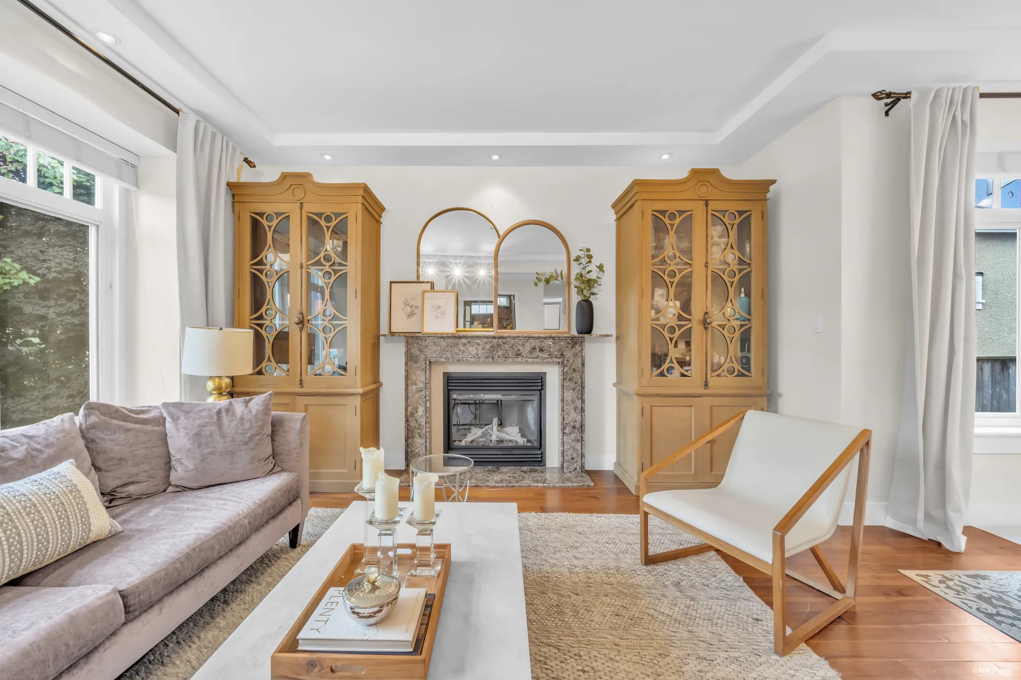 The fireplace in its stone surround, glazed cabinets either side, an armchair by the window
