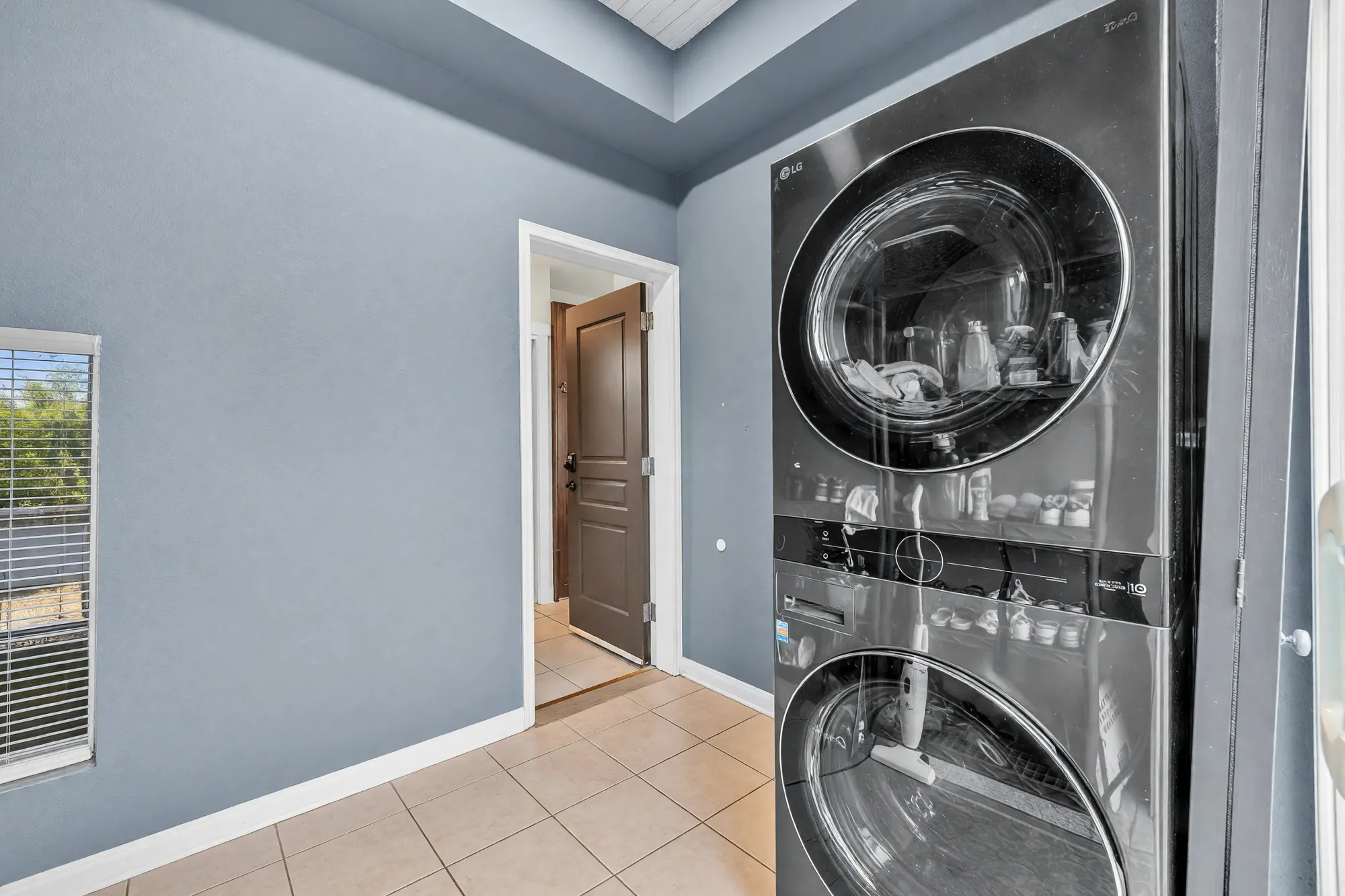 The laundry room off the kitchen: a stacked washer and dryer, a window, the door to the hall