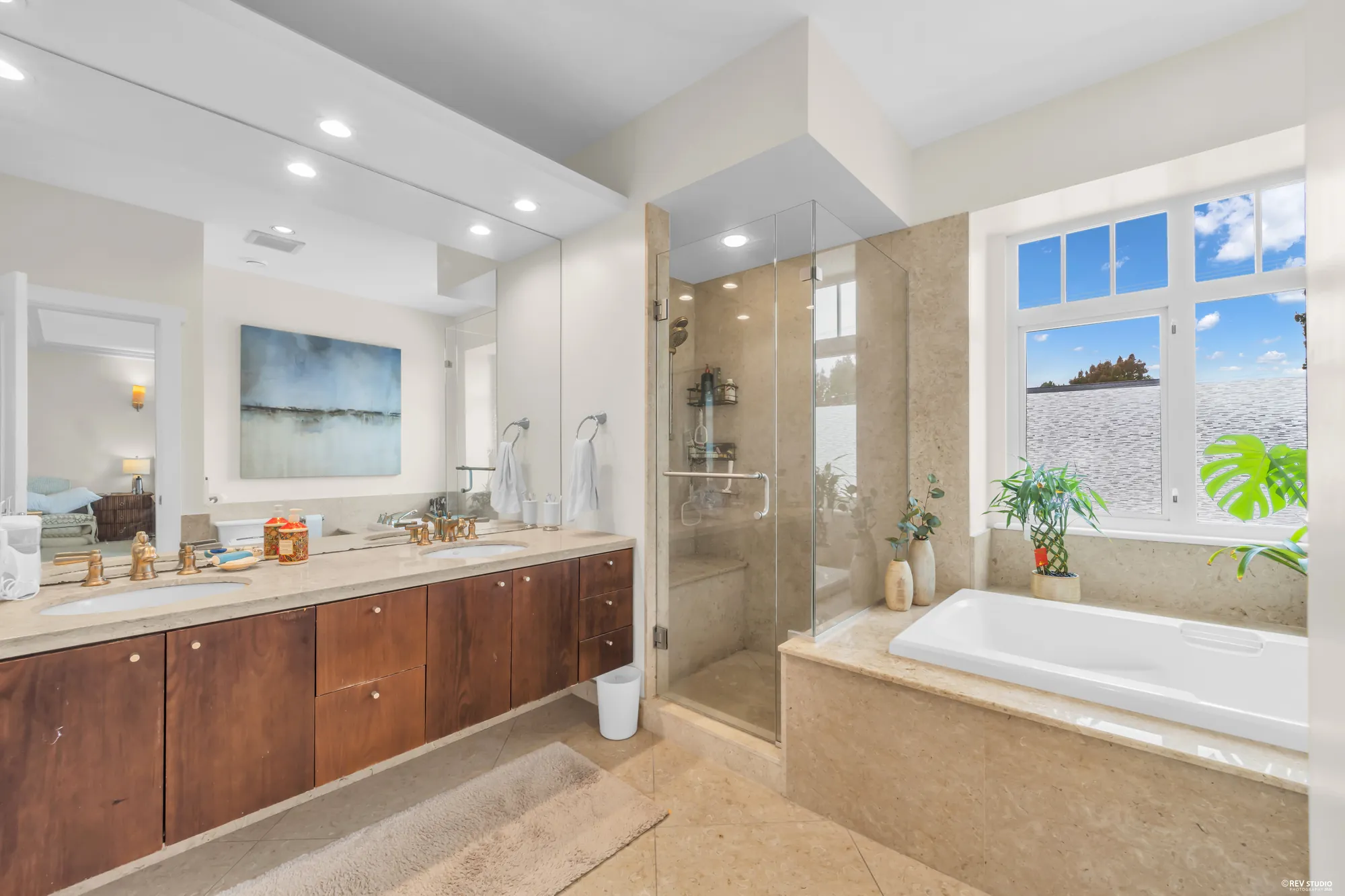 The primary bathroom: a long cherry vanity with two basins, a glass shower, a tub under the window