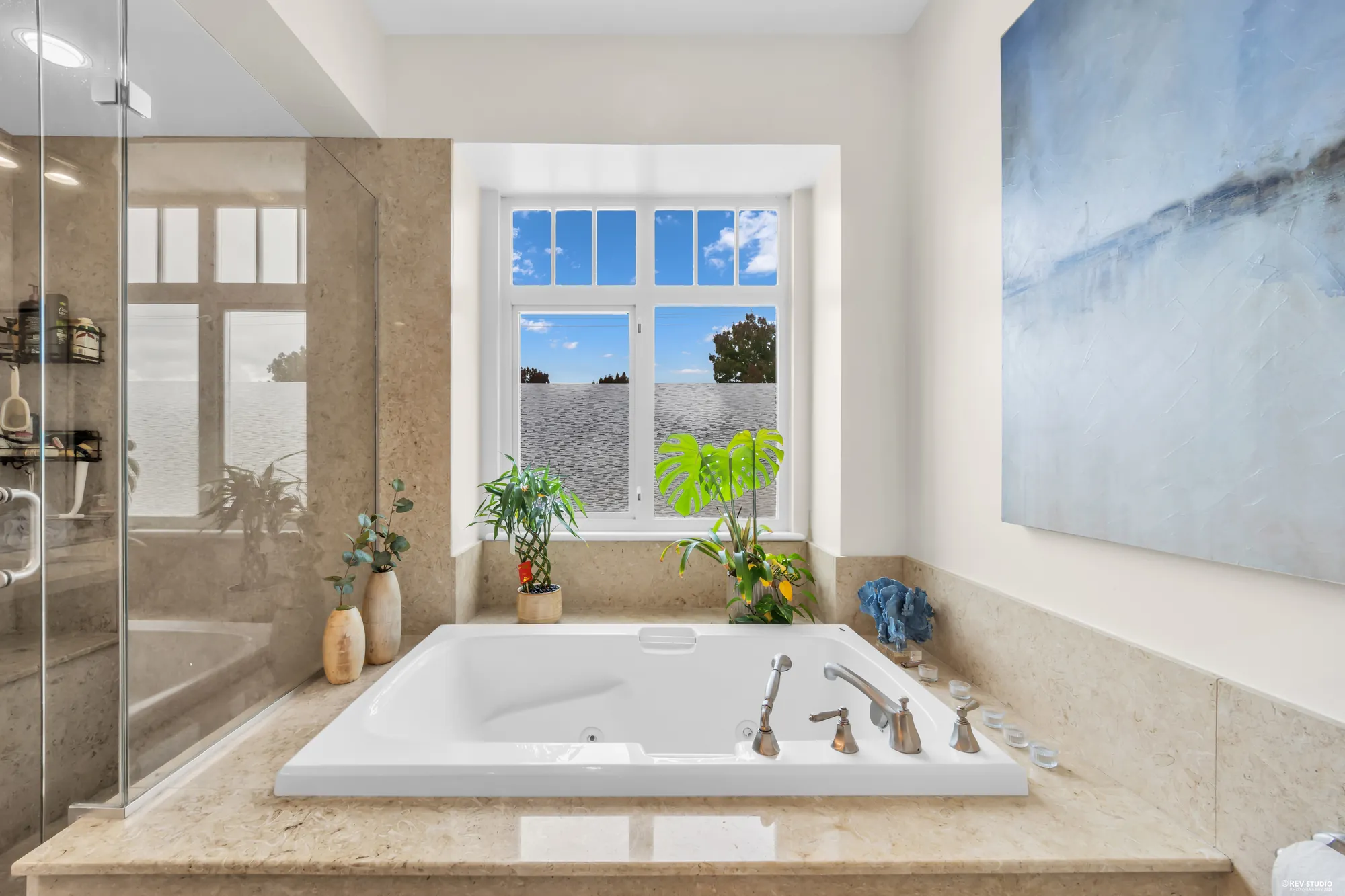The tub in its stone surround under the window, the shower beside it